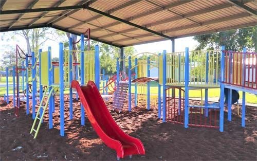 red, yellow and blue playground with red slide and bark softfall undercover